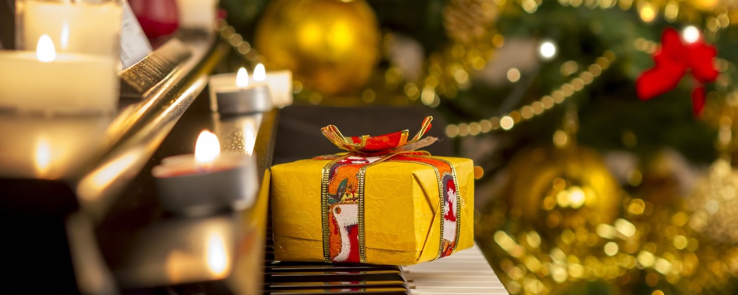 yellow gift box on piano with Christmas tree